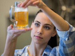 Eine junge Frau prüft das Bier im Bierglas