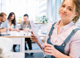 Junge Frau mit Unterlagen in der Hand in einem Büro